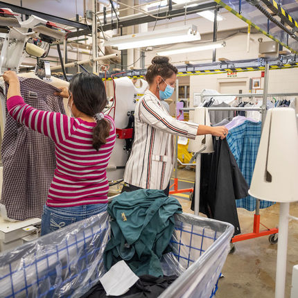 Jessica Jordan, production manager, (right) helps Rosita Tucubal at the shirt press station at St. Michael's Laundry. (Photo by Barbara Johnston/University of Notre Dame)