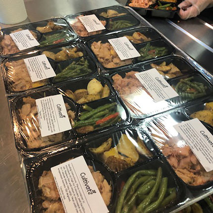 Prepared trays of food are ready to be placed in backpacks.