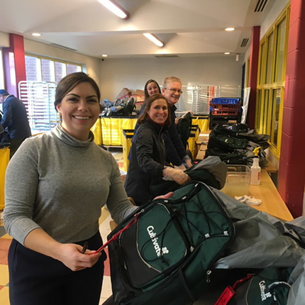 Emily Evans, assistant director of new media; Cindy Cubillo, event specialist; Curt Lynn, inventory and production coordinator; and Shannon Rooney, writer and content specialist, prepare backpacks for food.
