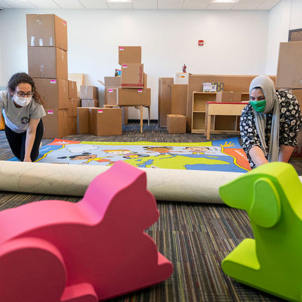 Celine Marcos and Samantha Musleh roll out a rug at the new Robinson Community Learning Center (RCLC) in South Bend. (Photo by Barbara Johnston/University of Notre Dame)
