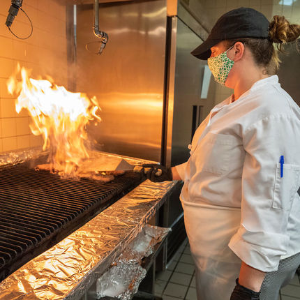 A food service worker flips burgers on the grill at South Dining Hall. (Photo by Barbara Johnston/University of Notre Dame)