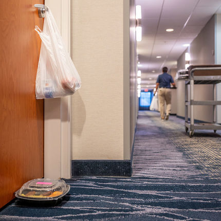 Bev Harbor delivers meals to students in quarantine. The main meal and a bag with water and fruit are left outside the room with a knock on the door. (Photo by Matt Cashore/University of Notre Dame)