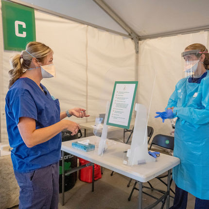 Ami Driscoll, assistant director of Medical Outreach chats with Angie Dale, RN (right) in the testing section at the COVID-19 Response Unit (CRU) in Notre Dame Stadium. (Photo by Barbara Johnston/University of Notre Dame)
