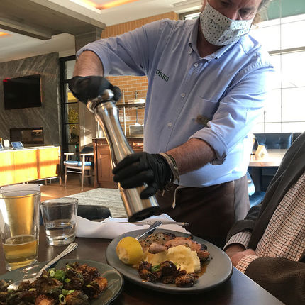 Edward Nolan, Rohr's server, grinds pepper over Greg Miller's meal. (Photo by Natalie Davis Miller)