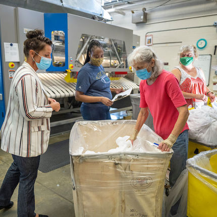 Jessica Jordan, production manager, (left) works with Wieslawa Ruchniak, crew leader, Karen Fulford and Karen Qureshi (right) ironing table linens at St. Michael's Laundry. (Photo by Barbara Johnston/University of Notre Dame)