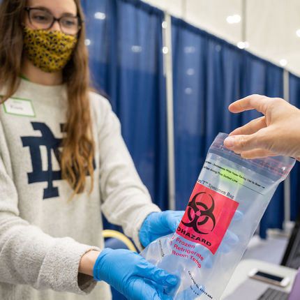 A student worker holds out a biohazard bag into
which the person being tested deposits the vial
that contains the saliva sample. The bags are
transported to McCourtney Hall to be analyzed
in a lab.