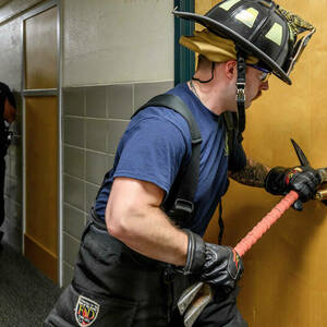 A firefighter breeches a door.